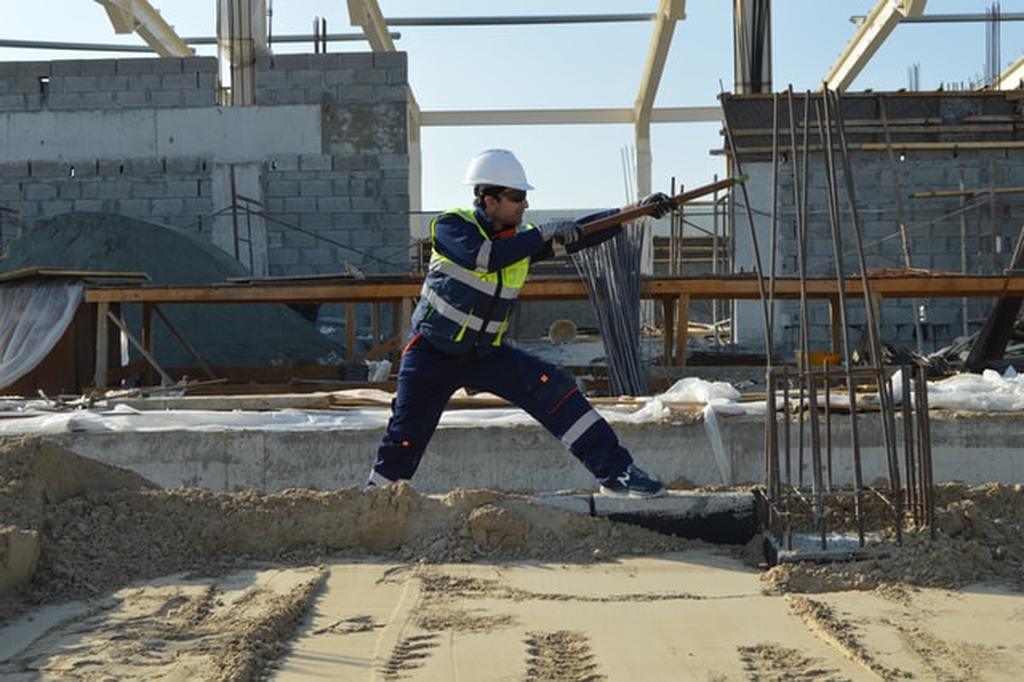 Trabalhador uniformizado salta sobre a instalação de uma manta asfáltica para aumentar seu tempo de duração