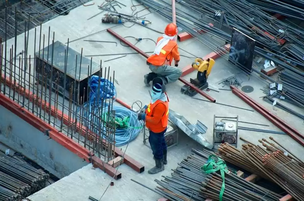 Trabalhadores na obra demonstrando como funciona a manta asfáltica para laje